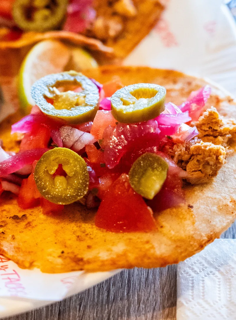Twee open soft tacos op een bord met het logo van Cantina y Tacos